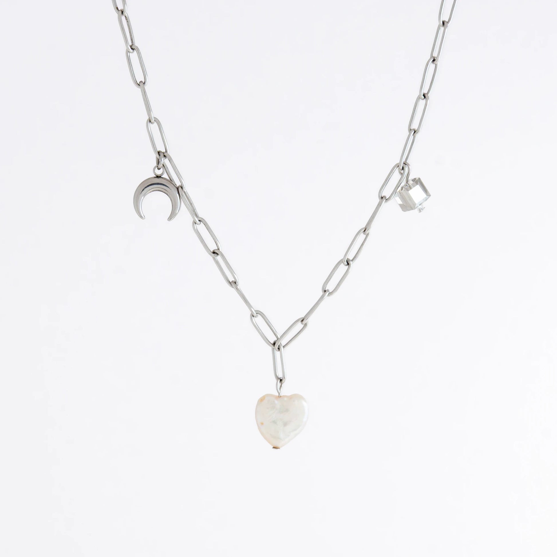 Silver chain charm necklace with pearl pendants, glass bead, and star pendants on a light gray background