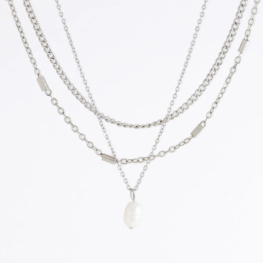 Silver stainless steel layered necklace set with a curb chain, a bar link chain and a dainty pearl pendant necklace on a light gray background