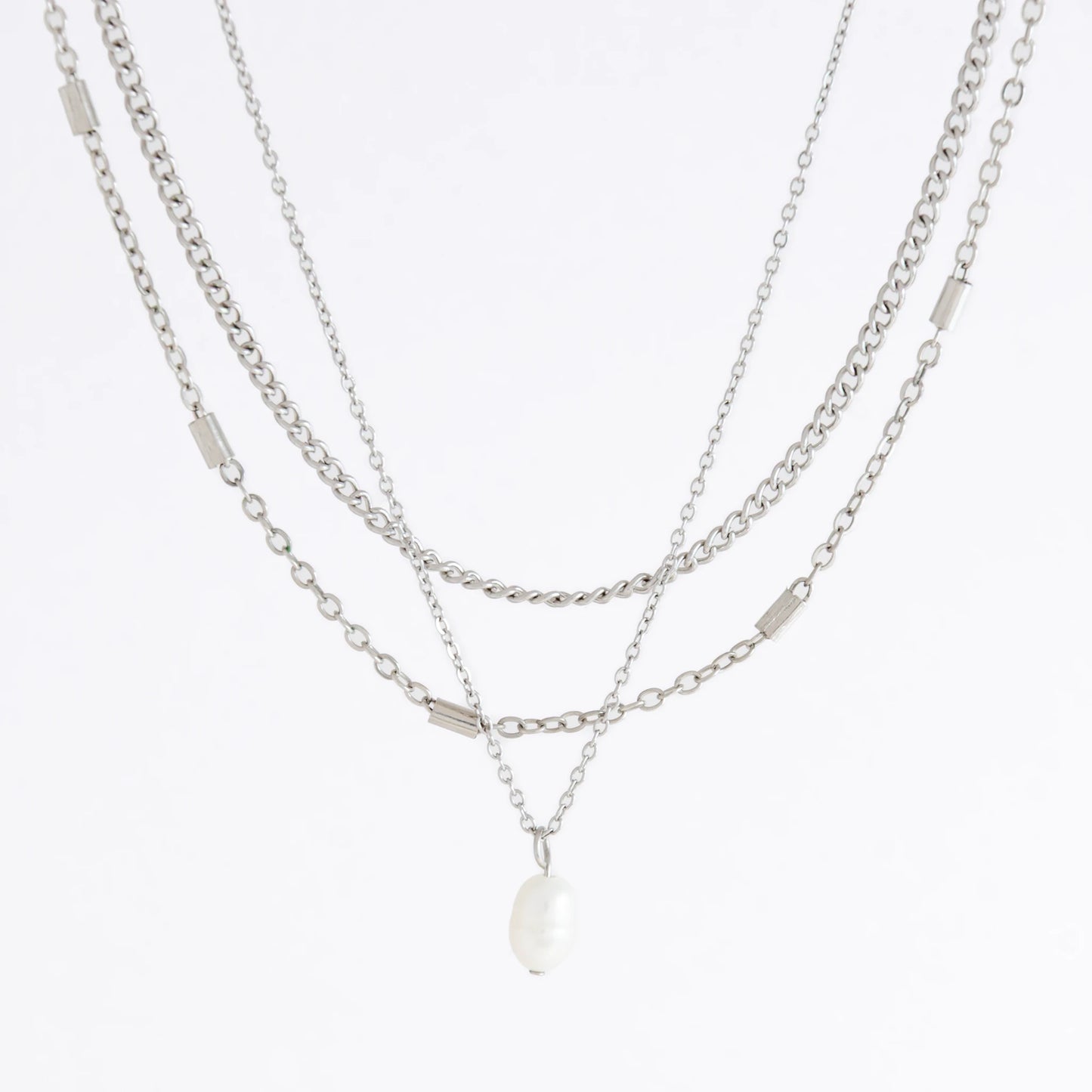 Silver stainless steel layered necklace set with a curb chain, a bar link chain and a dainty pearl pendant necklace on a light gray background