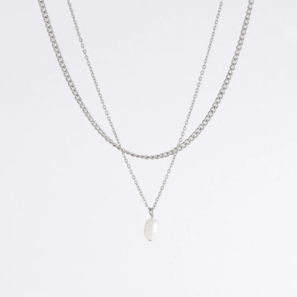 Silver stainless steel layered necklace set with a curb chain and a dainty pearl pendant necklace on a light gray background