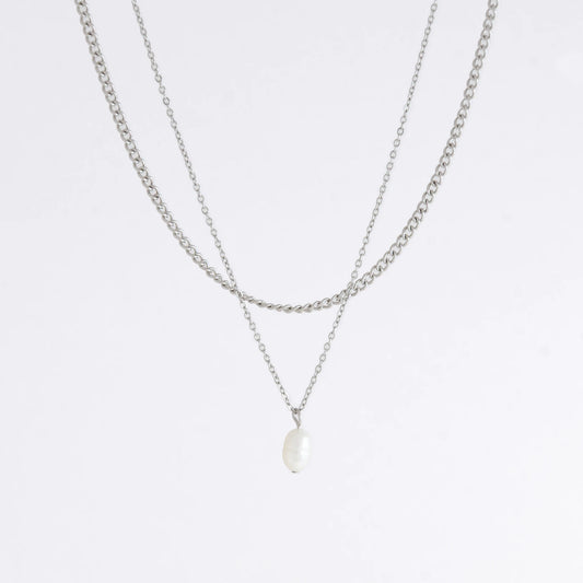 Silver stainless steel layered necklace set with a curb chain and a dainty pearl pendant necklace on a light gray background