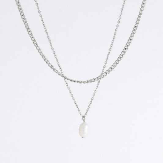 Silver stainless steel layered necklace set with a curb chain and a dainty pearl pendant necklace on a light gray background