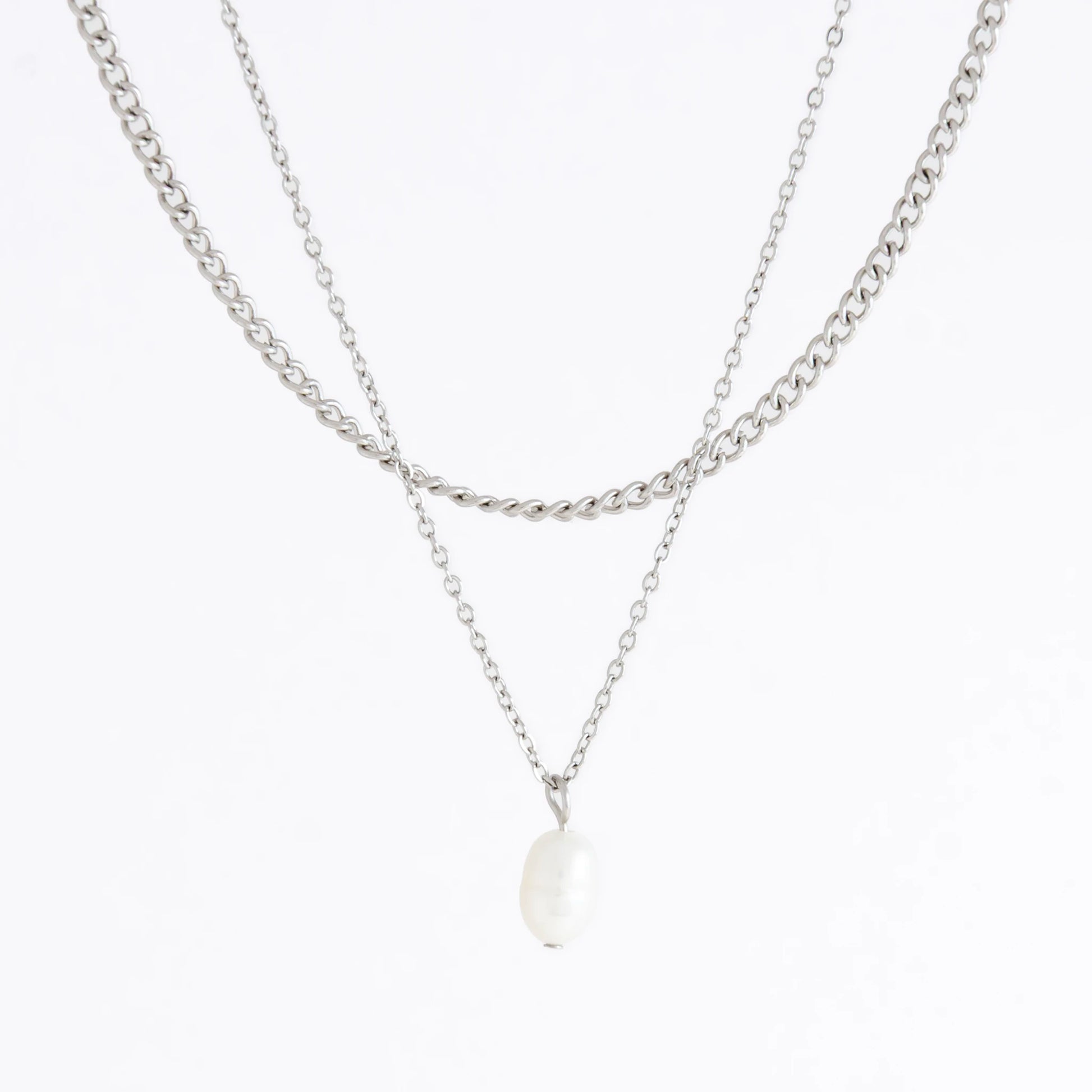Silver stainless steel layered necklace set with a curb chain and a dainty pearl pendant necklace on a light gray background