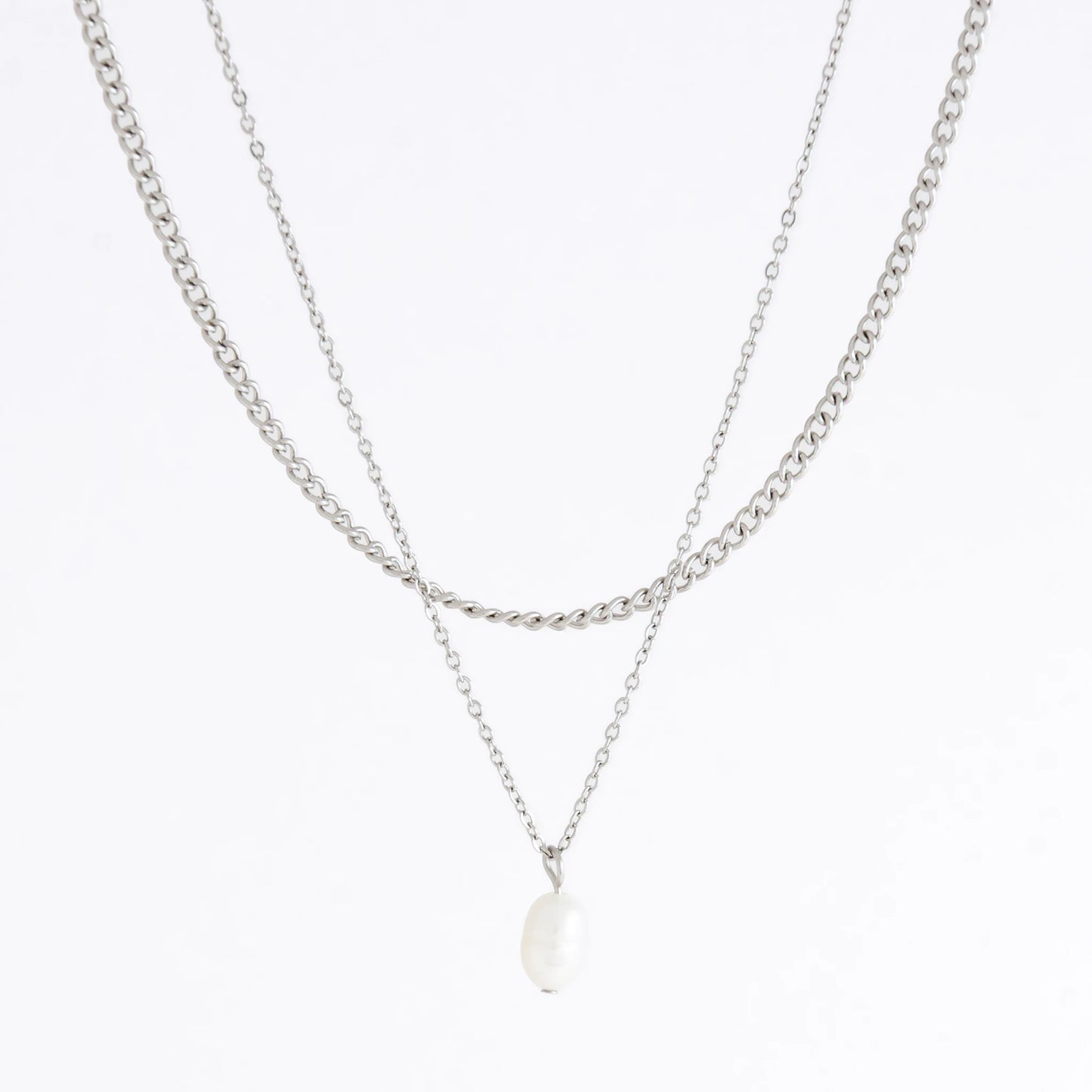 Silver stainless steel layered necklace set with a curb chain and a dainty pearl pendant necklace on a light gray background