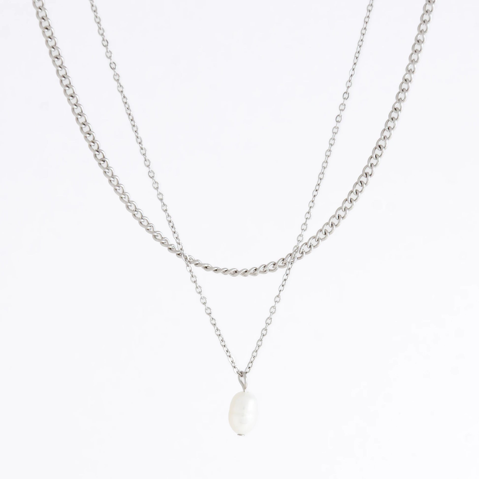 Silver stainless steel layered necklace set with a curb chain and a dainty pearl pendant necklace on a light gray background