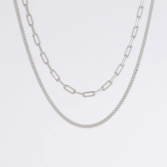 Two silver chain necklaces on a light gray background