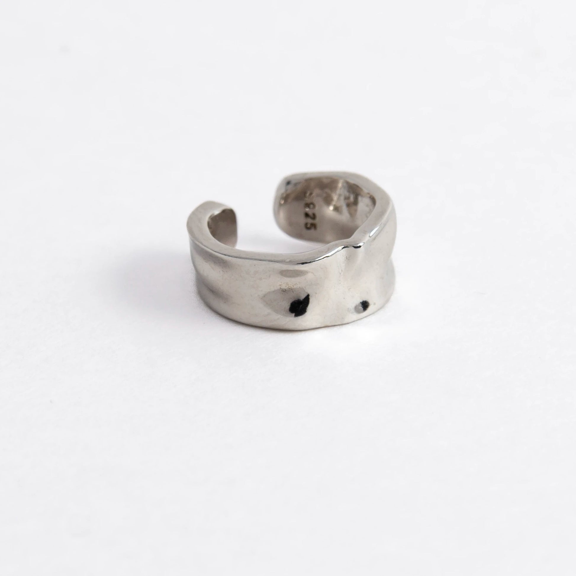 Silver ear cuff on a light gray background