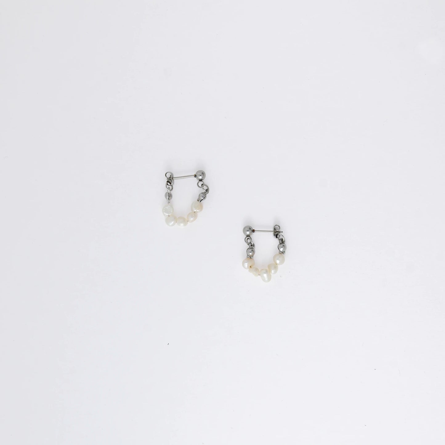 A pair of silver-colored thin pearl hoop earrings, displayed against a white background