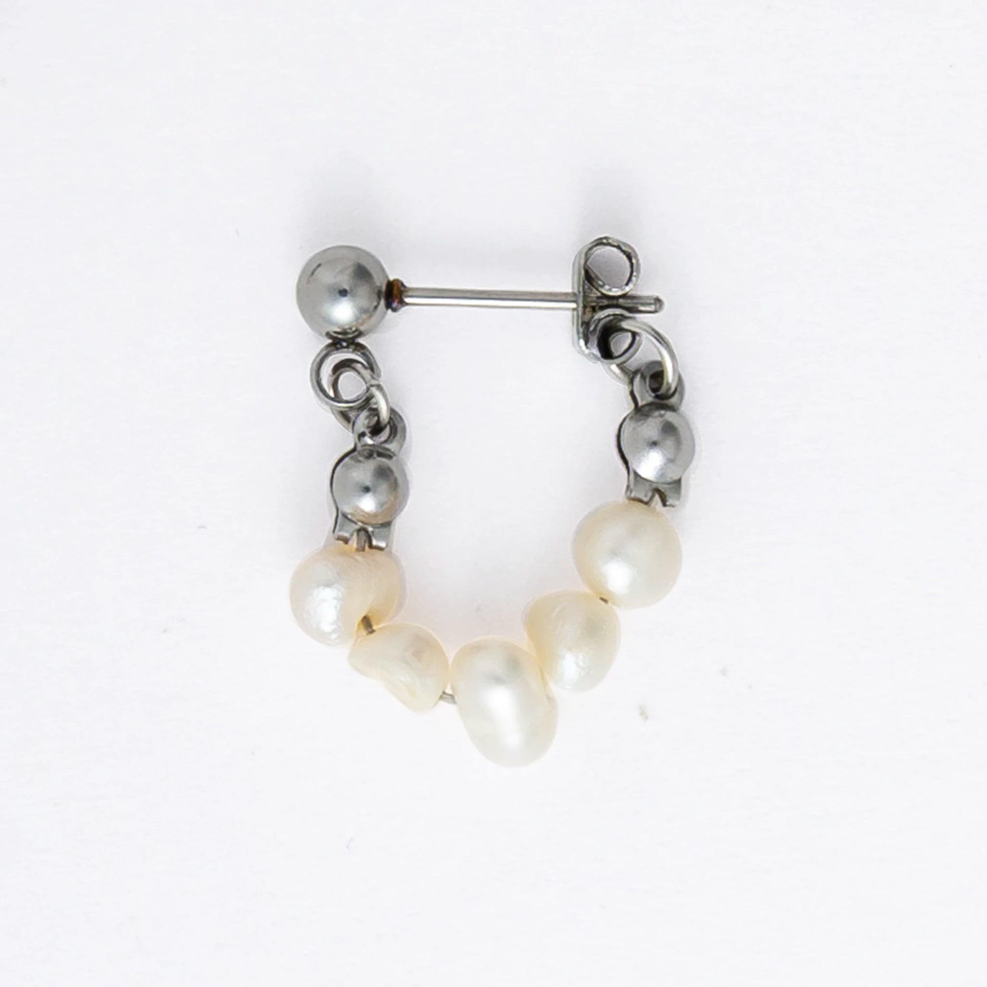 A pair of silver-colored thin pearl hoop earrings, displayed against a white background