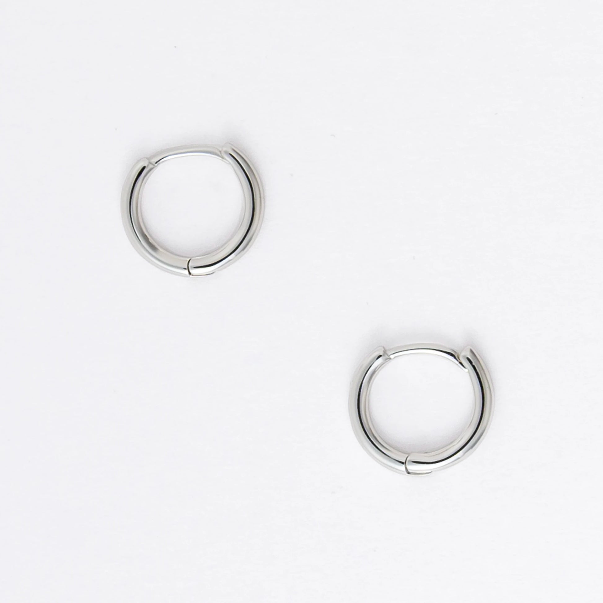 Two silver hoop earrings on a light gray background
