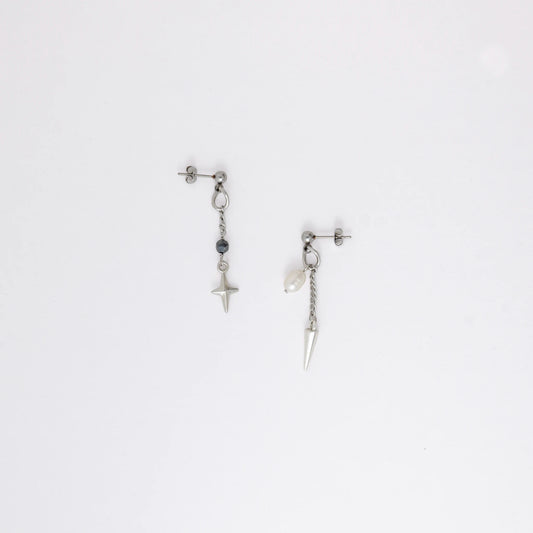 Pair of silver stainless steel ball stud drop earrings with a chain and star charm and a pearl and spike charm on a white background