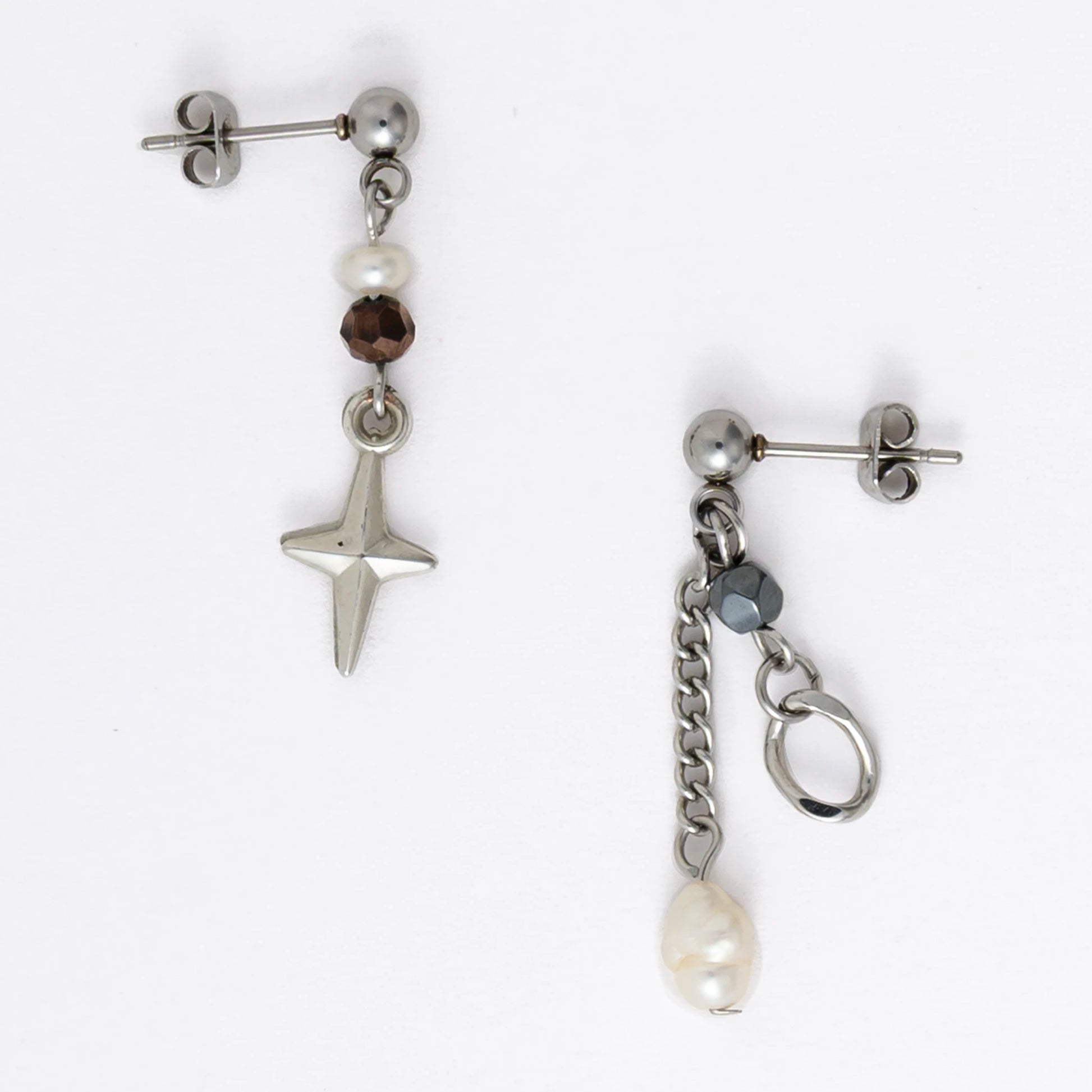 Pair of silver stainless steel ball stud drop earrings with orange and black glass beads and star and pearl charm with unique designs on a white background