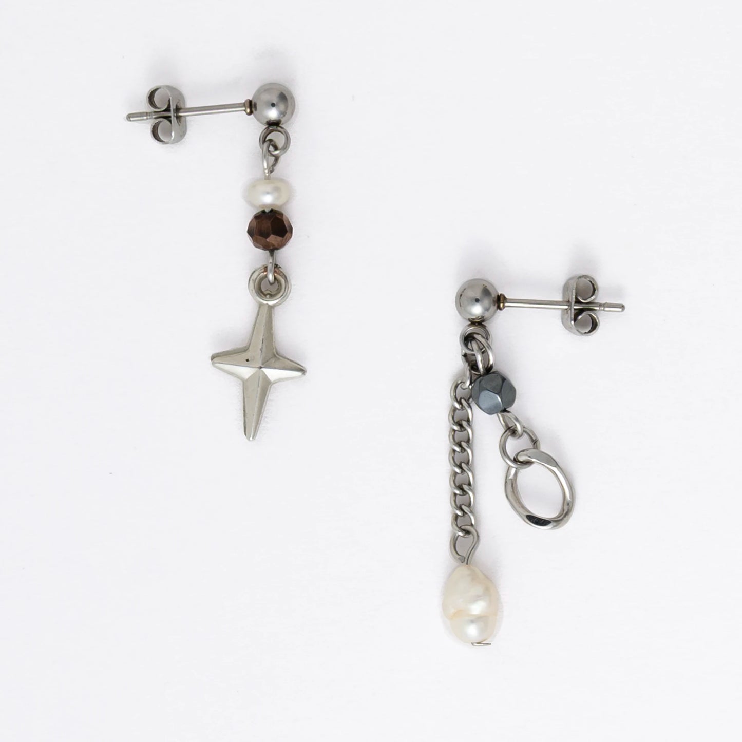 Pair of silver stainless steel ball stud drop earrings with orange and black glass beads and star and pearl charm with unique designs on a white background