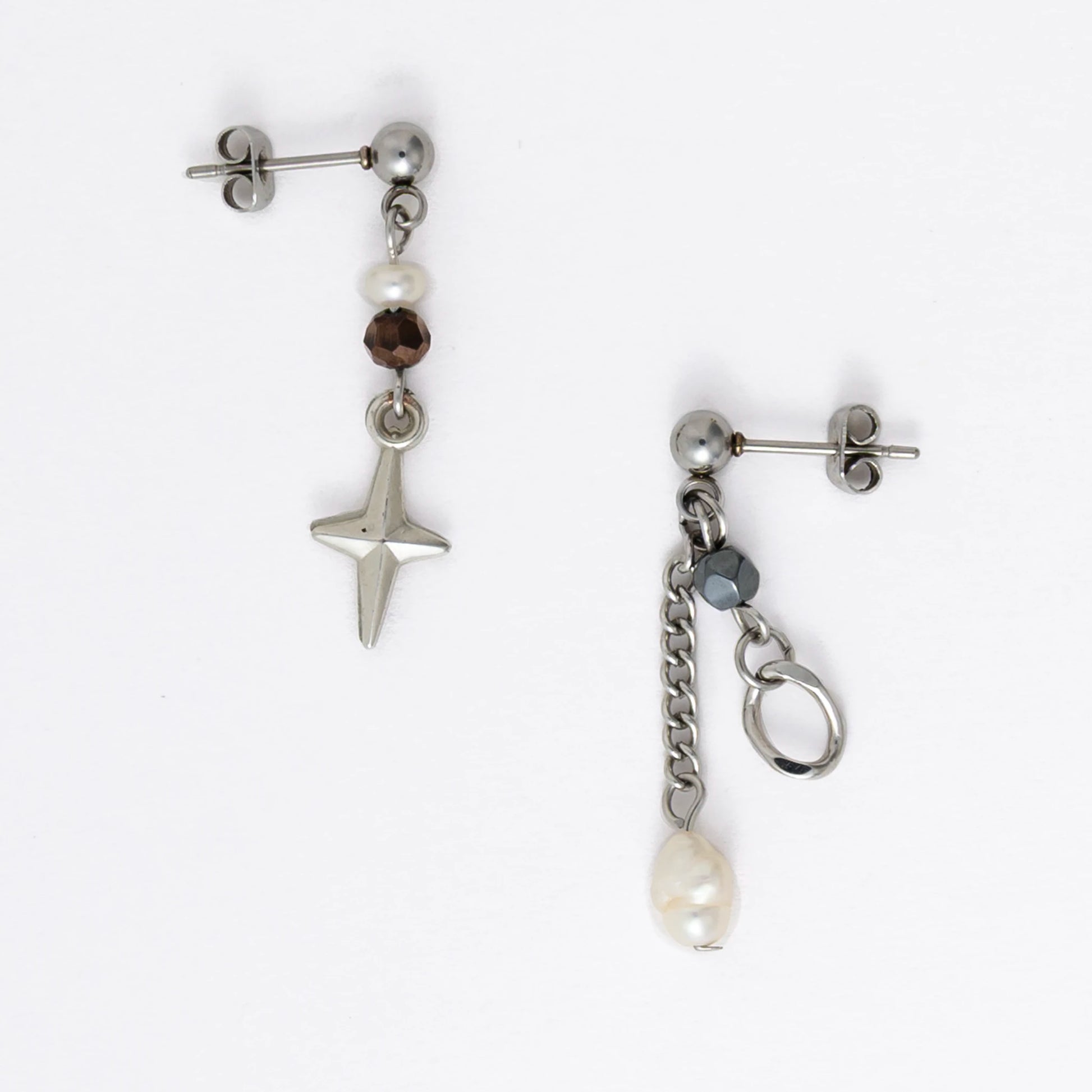 Pair of silver stainless steel ball stud drop earrings with orange and black glass beads and star and pearl charm with unique designs on a white background