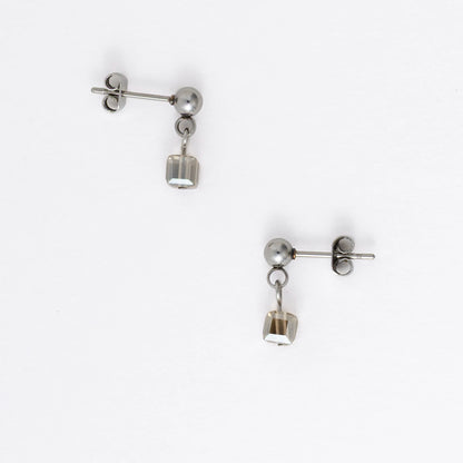 Pair of silver stainless steel ball stud earrings with sugar cube gray glass beads on a white background