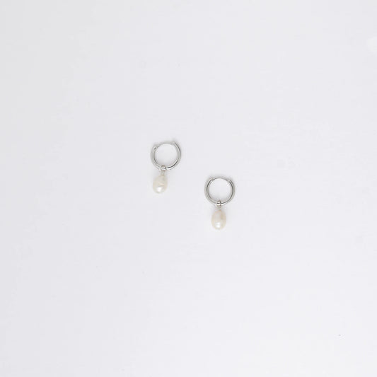 Pair of silver hoop earrings with pearl drops on a light gray background