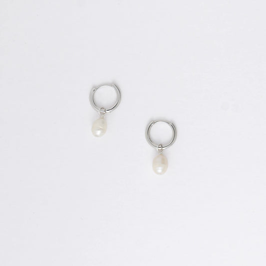 Pair of silver hoop earrings with pearl drops on a light gray background