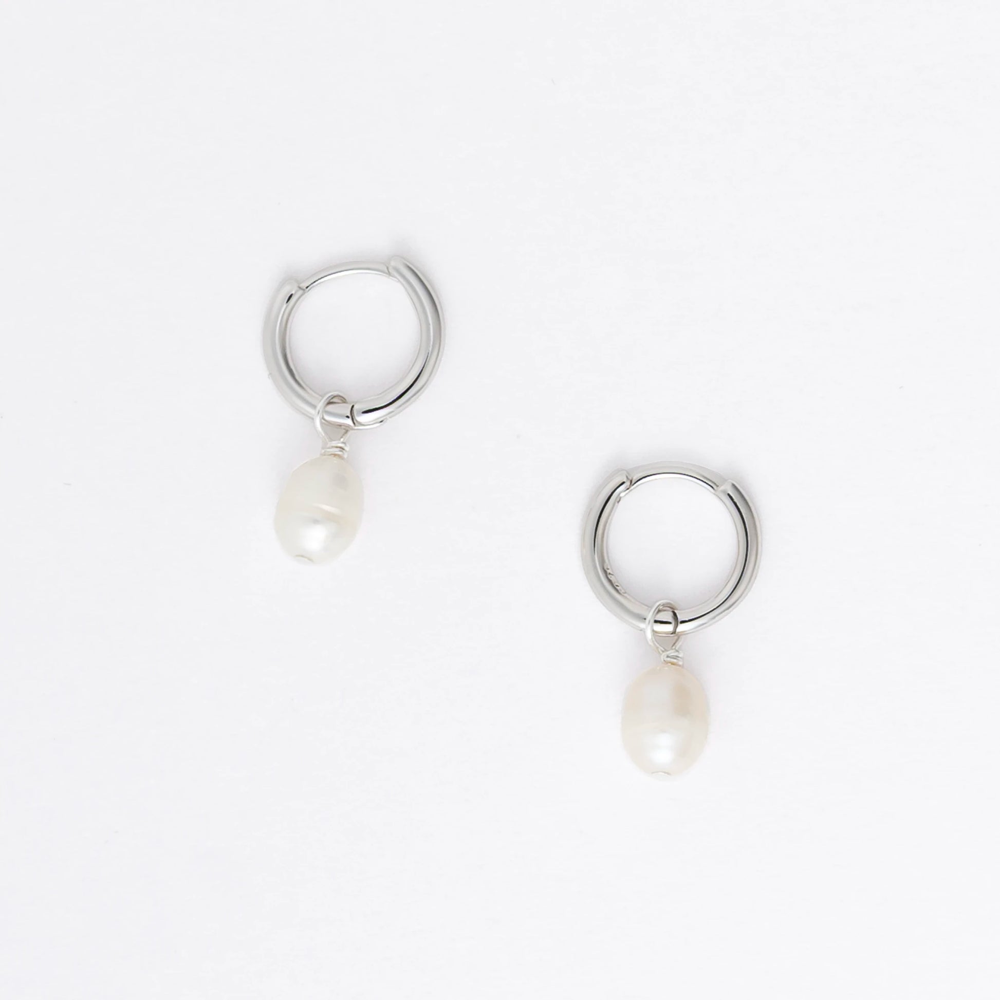 Pair of silver hoop earrings with pearls and a black bead on a white background
