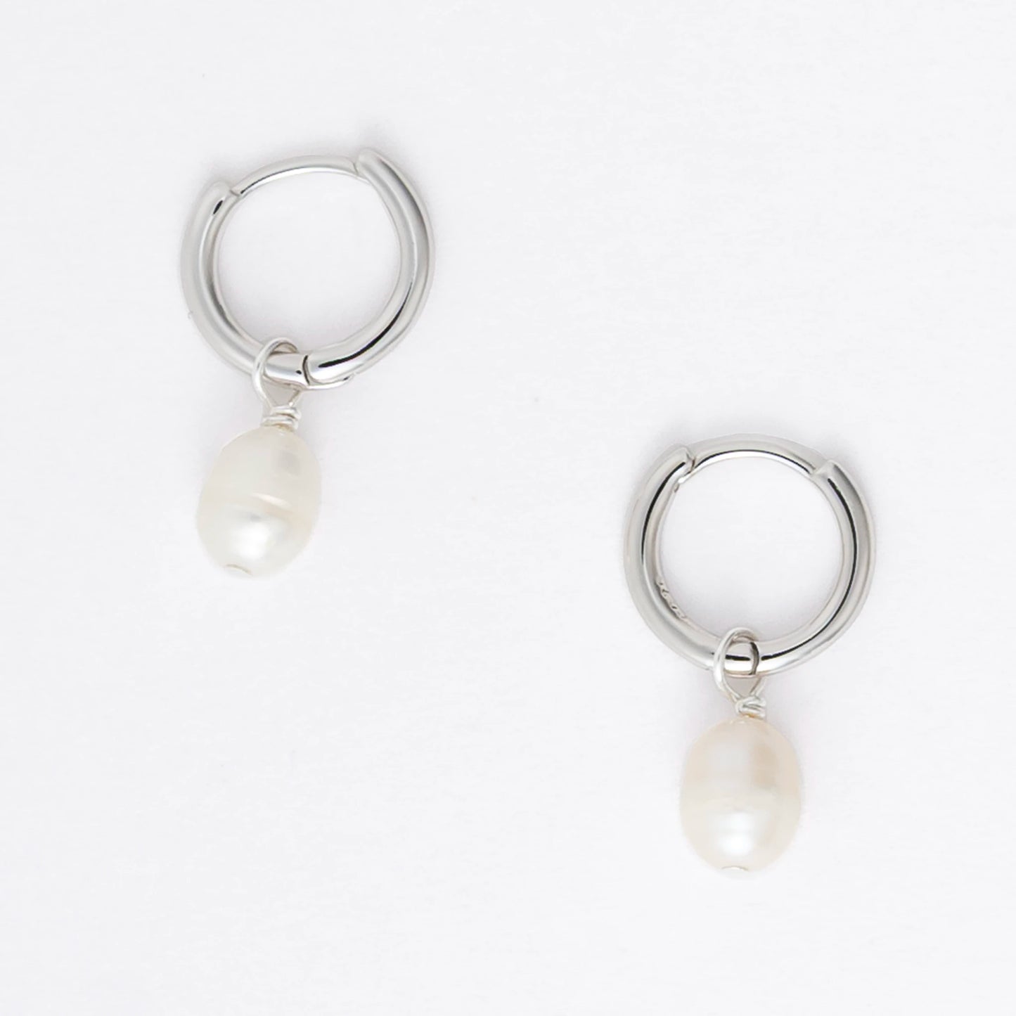 Pair of silver hoop earrings with pearl drops on a light gray background