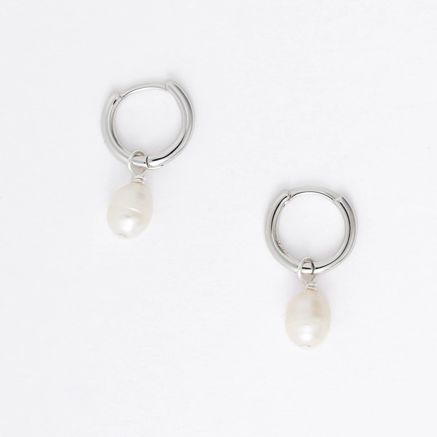 Pair of silver hoop earrings with pearl drops on a light gray background
