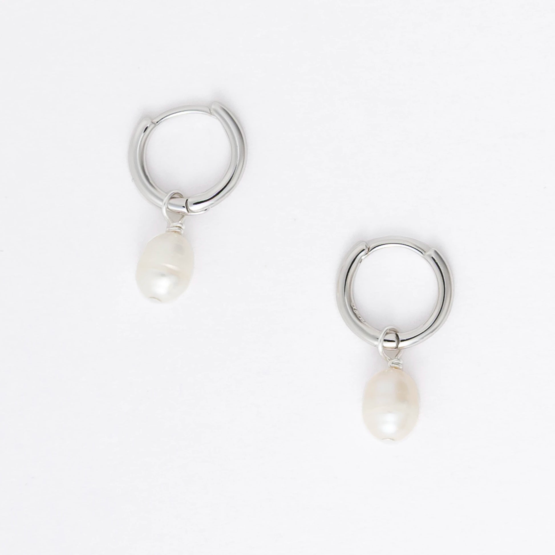 Pair of silver hoop earrings with pearl drops on a light gray background