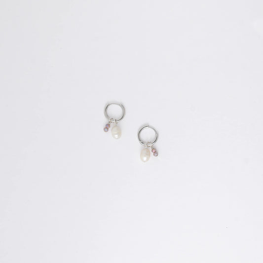 Pair of silver earrings with small pearls on a light gray background