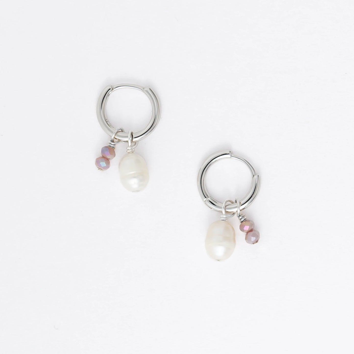 Pair of silver hoop earrings with pearls and a black bead on a white background