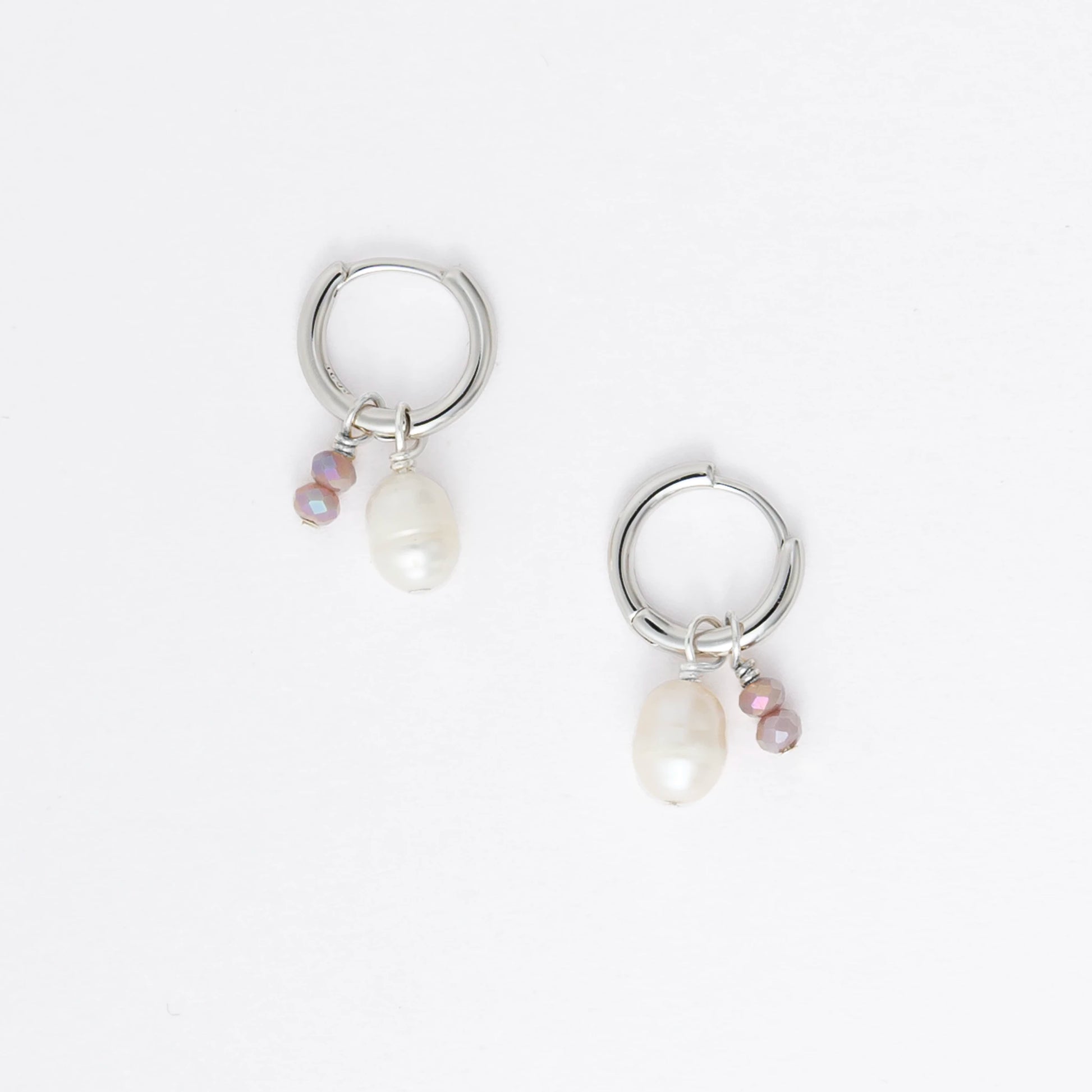 Pair of silver hoop earrings with pearls and a black bead on a white background