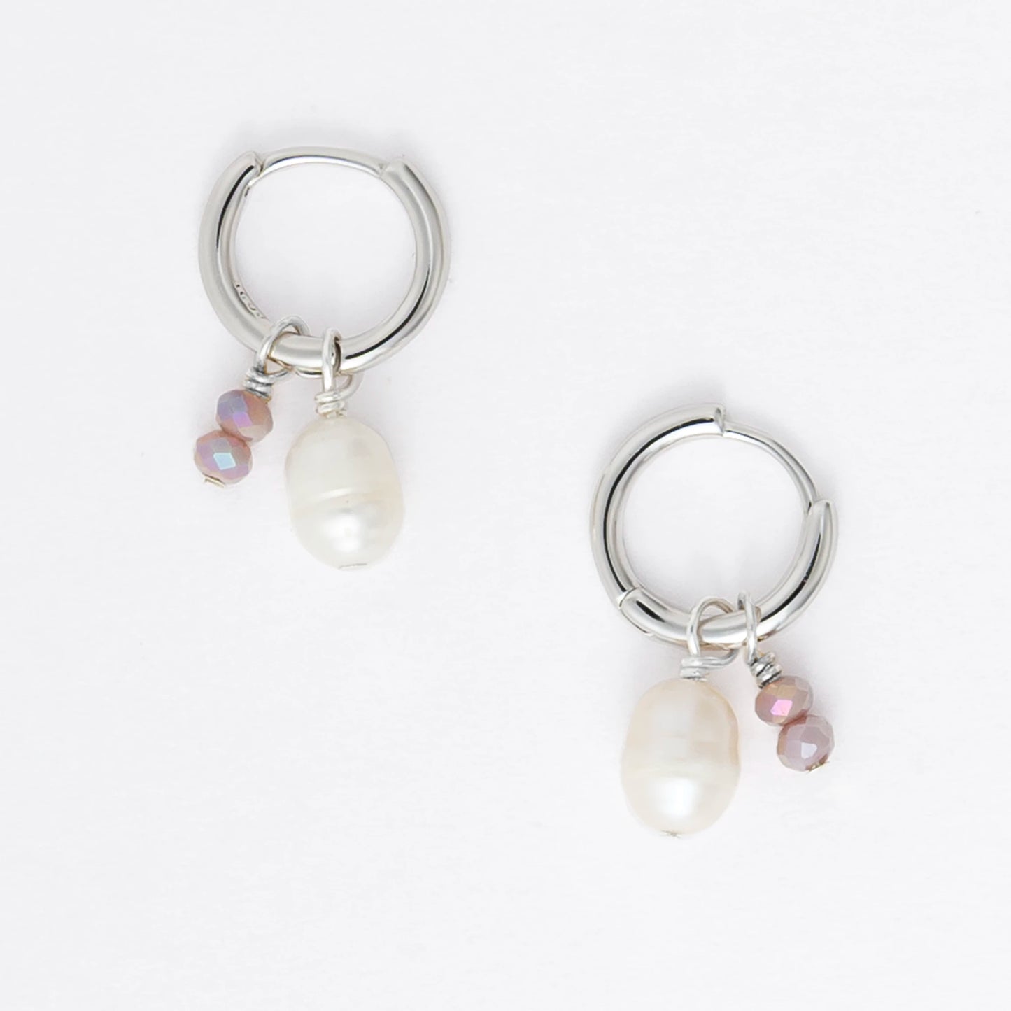 Pair of silver earrings with small pearls on a light gray background