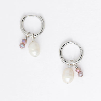 Pair of silver earrings with small pearls on a light gray background