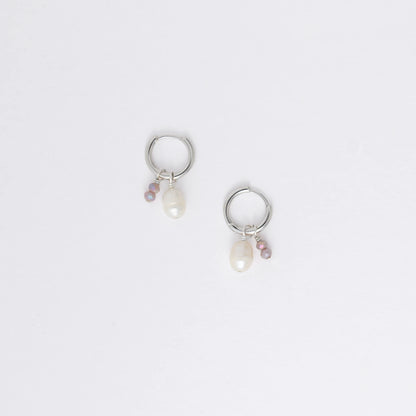 Pair of silver hoop earrings with pearl and gemstone charms on a light gray background
