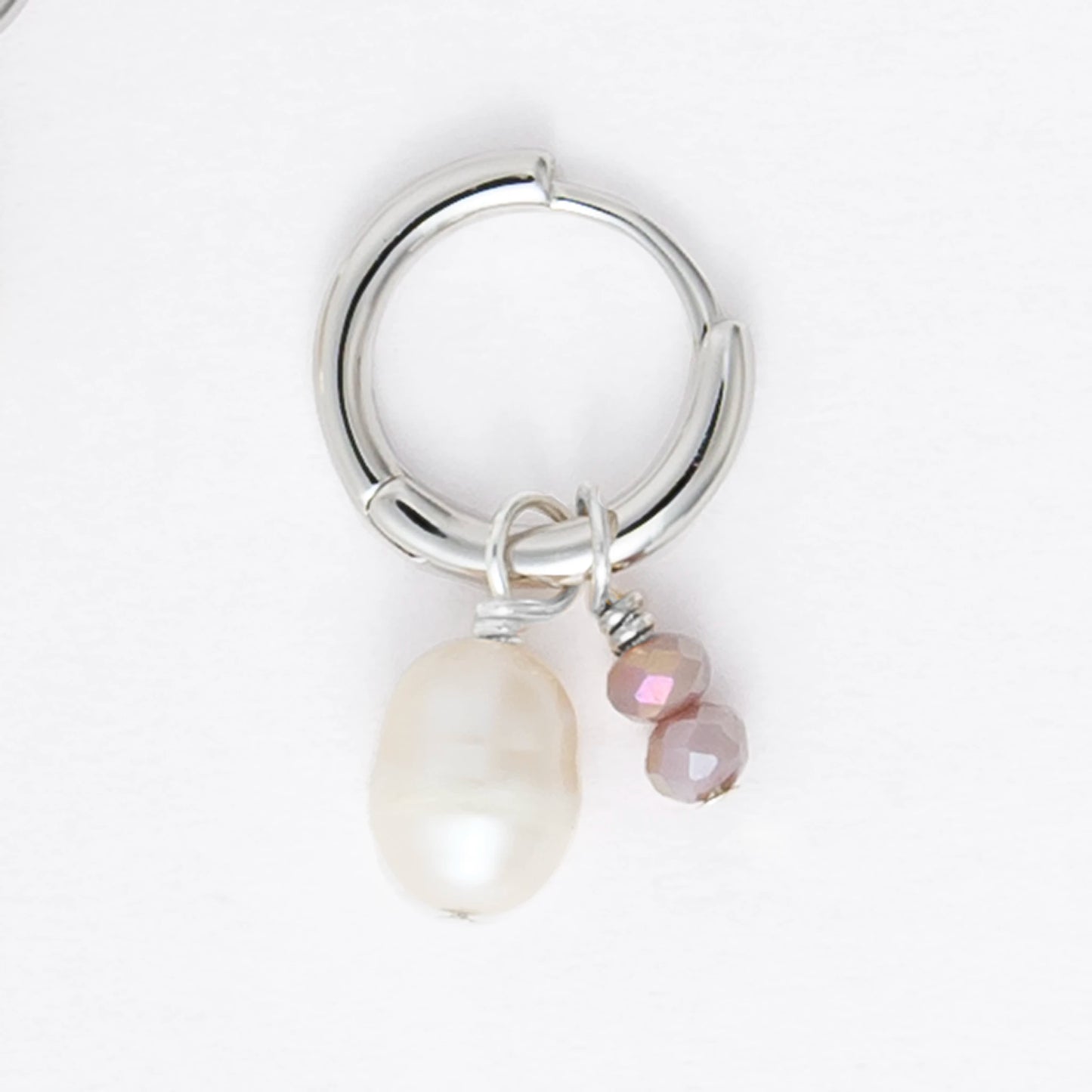 Pair of silver earrings with small pearls on a light gray background