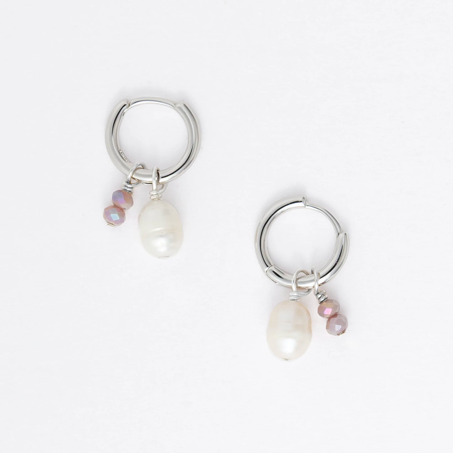Pair of silver earrings with small pearls on a light gray background