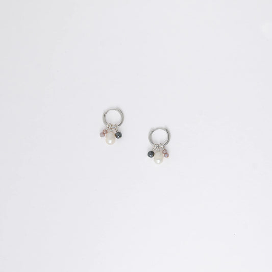 Pair of silver hoop earrings with pearls and a black bead on a white background