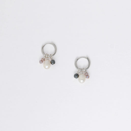 Pair of silver hoop earrings with pearls and a black bead on a white background