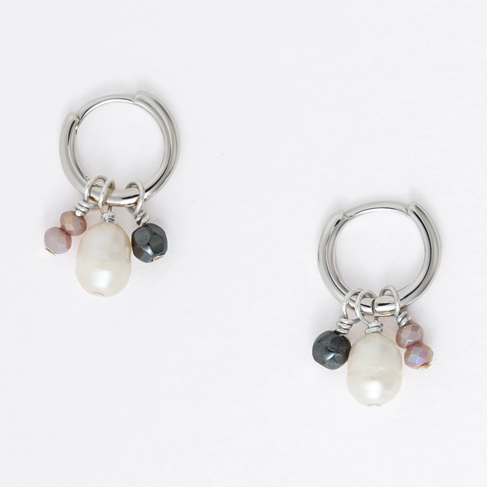 Pair of silver hoop earrings with pearls and a black bead on a white background