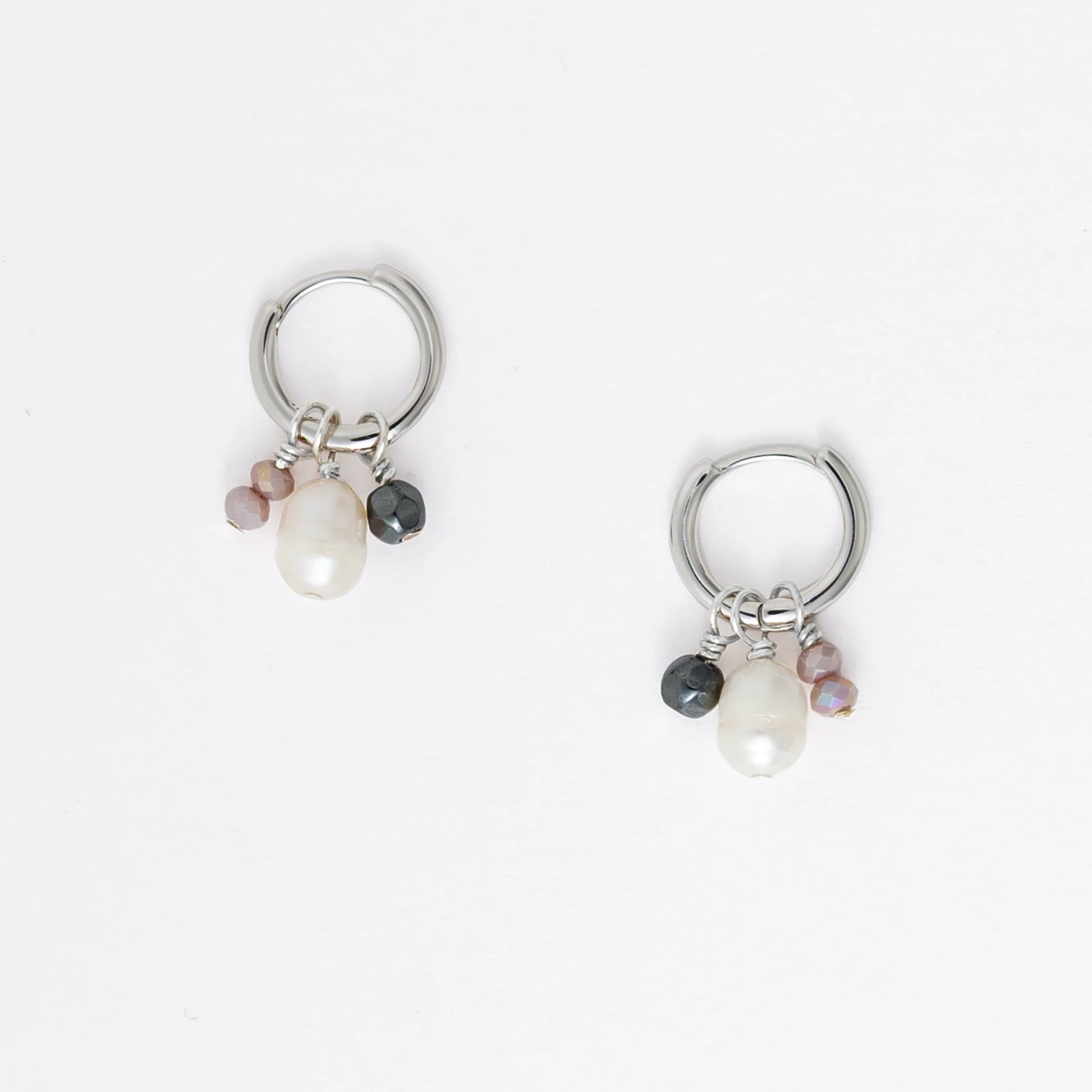 Pair of silver hoop earrings with pearl and gemstone charms on a light gray background