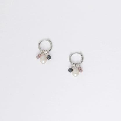 Pair of silver hoop earrings with pearl and gemstone charms on a light gray background