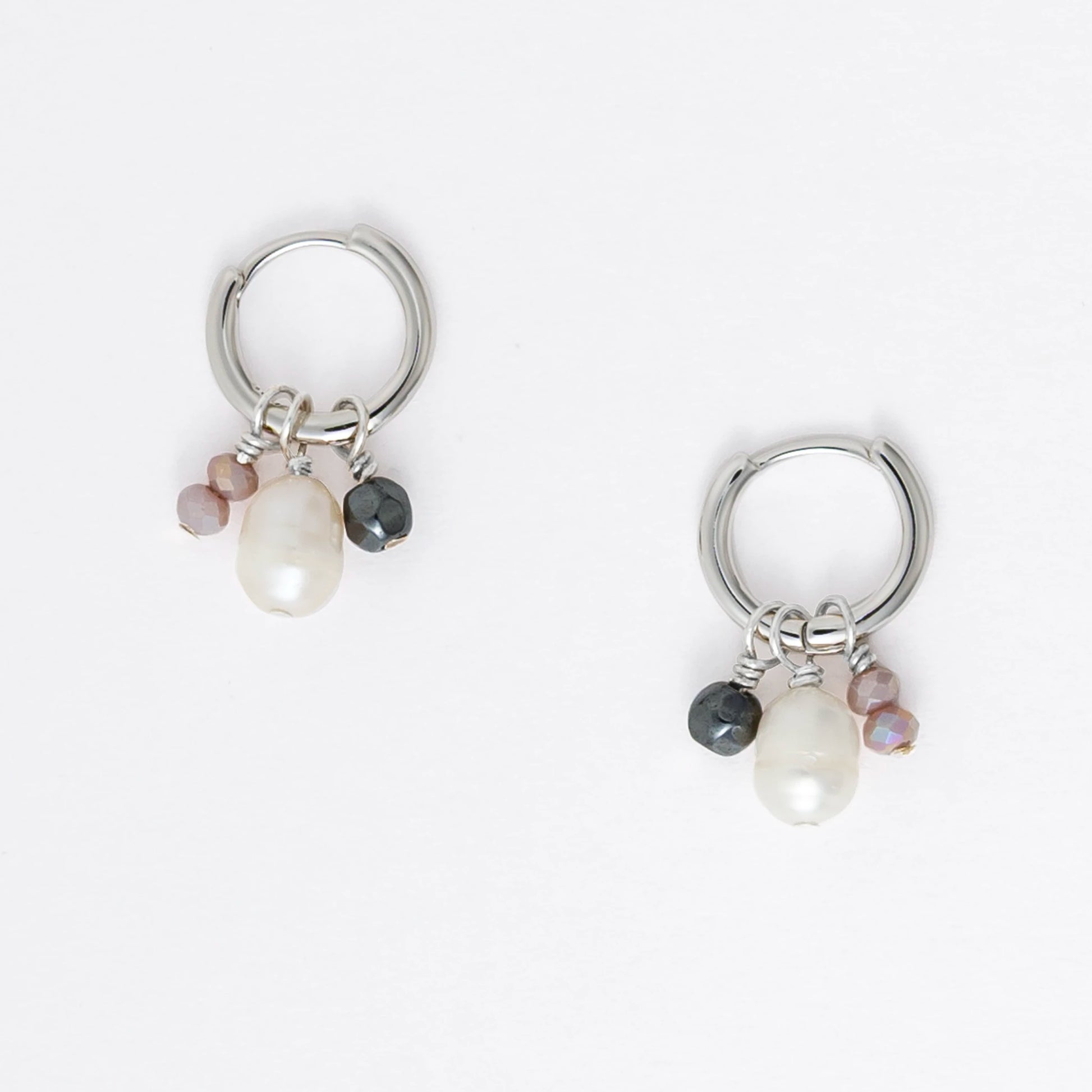 Pair of silver hoop earrings with pearls and a black bead on a white background