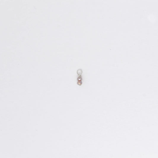 Two small purple glass bead charm on a white background