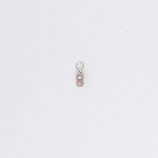 Two small purple glass bead charm on a white background