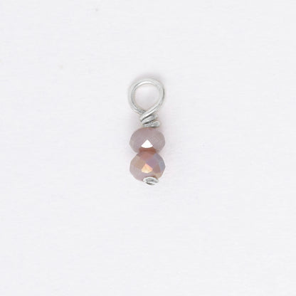 Two small purple glass bead charm on a white background