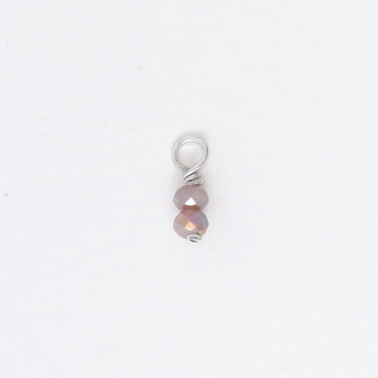 Two small purple glass bead charm on a white background