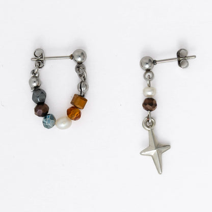 Pair of stainless steel hoop earrings with small beads and drop earrings with star charm on a white background