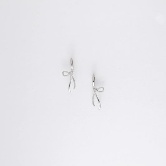 Pair of silver earrings with bow design on a light gray background