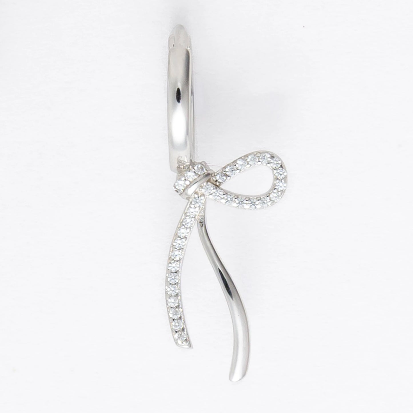 Pair of silver earrings with bow design on a light gray background