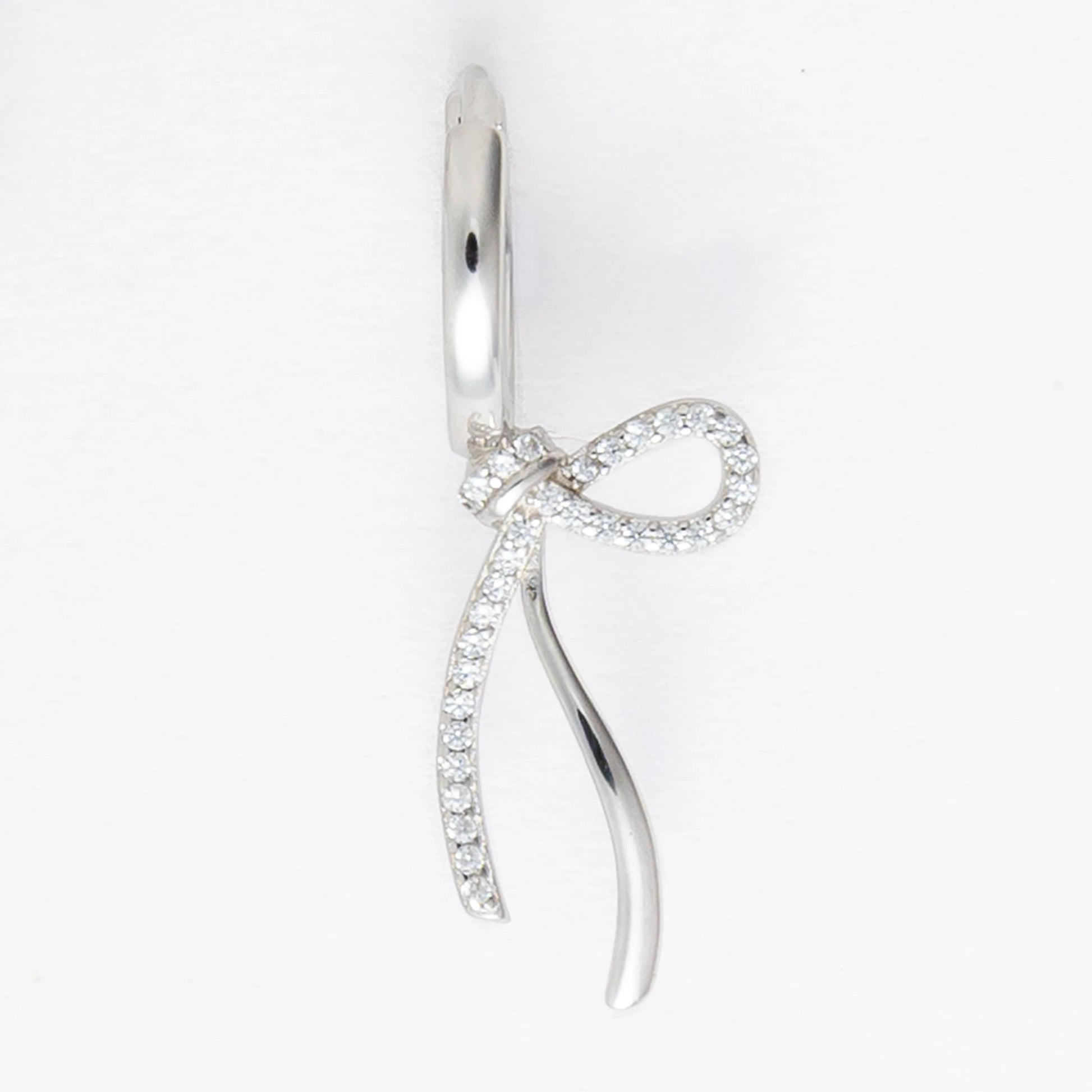 Pair of silver earrings with bow design on a light gray background