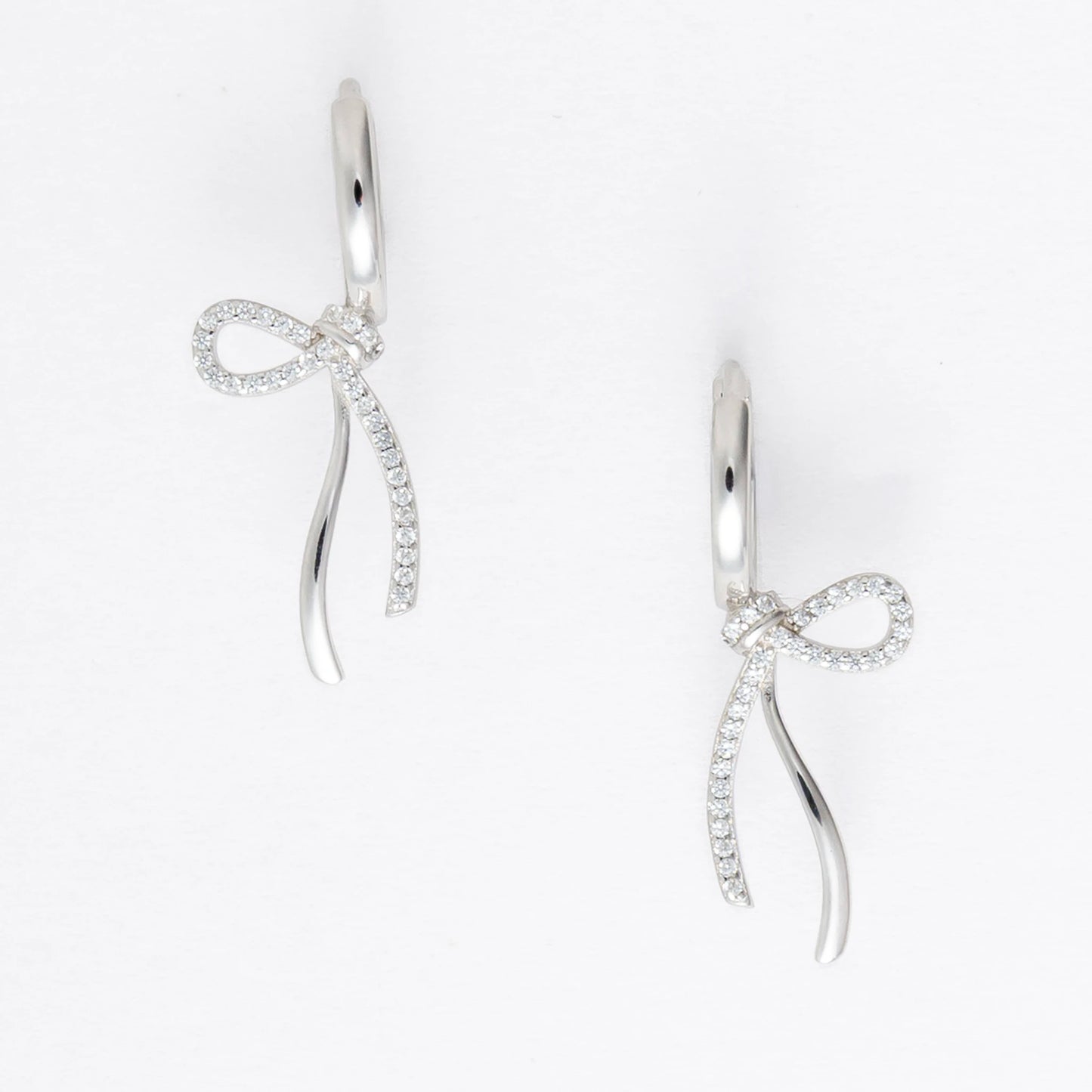 Pair of silver earrings with bow design on a light gray background