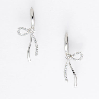 Pair of silver earrings with bow design on a light gray background