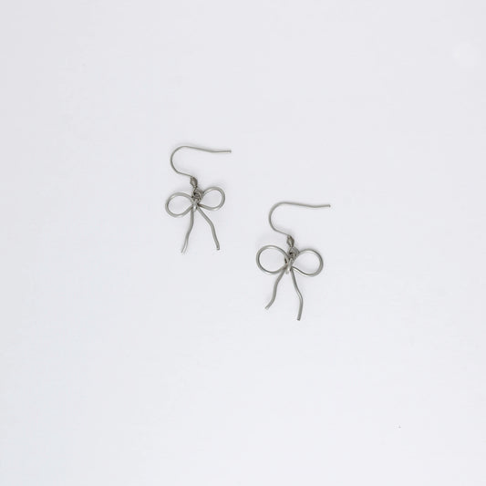 A pair of silver-toned ribbon bow drop earrings on a white background.